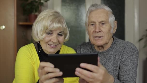Vrij volwassen senior paar grootouders genieten van online winkelen op tablet thuis — Stockvideo
