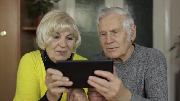 Vrij volwassen senior paar grootouders genieten van online winkelen op tablet thuis — Stockvideo