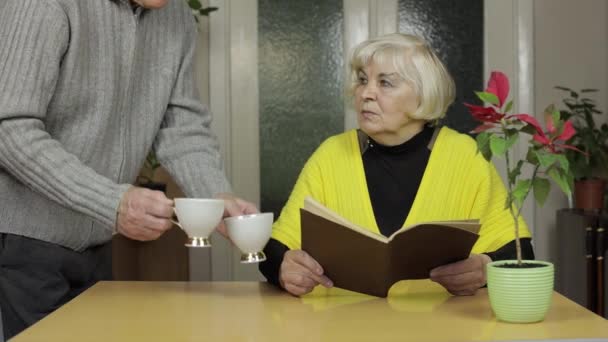 Feliz viejo viejo pareja sentarse en mesa en casa disfrutando de tiempo libre beber té — Vídeos de Stock