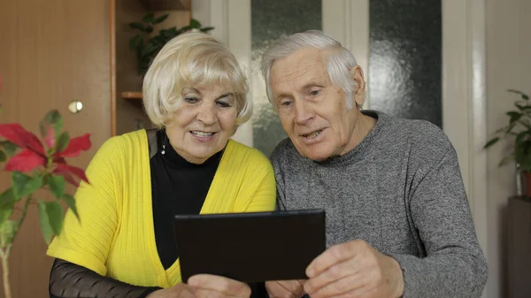 Bastante madura pareja de abuelos haciendo videollamada con teléfono en casa — Foto de Stock