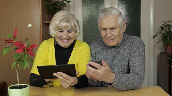 Pareja mayor bastante madura abuelos disfrutan de compras en línea en el teléfono, tableta — Foto de Stock