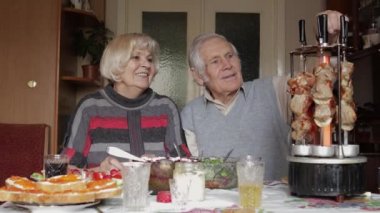 Mutlu yaşlı büyükanne ve büyükbaba çiftimiz evde ızgarada barbekü pişiriyor.