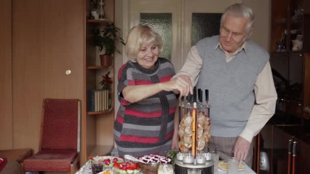 Mutlu yaşlı büyükanne ve büyükbaba çiftimiz evde ızgarada barbekü pişiriyor. — Stok video
