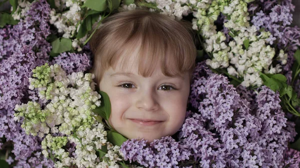 Cute girl dziecko patrząc z bukietu kwiatów lilii wokół jej twarzy — Zdjęcie stockowe