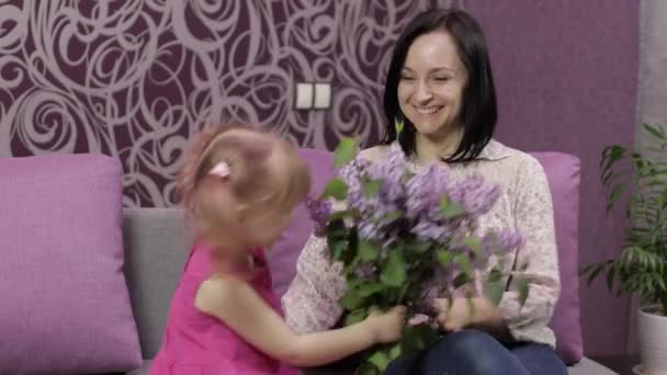 Lilla dotter barn gratulerar sin mor med bukett av syrenblommor — Stockvideo