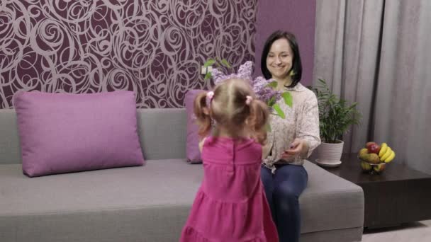 Criança pequena filha parabeniza sua mãe com buquê de flores lilás — Vídeo de Stock