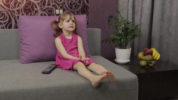 Petit enfant assis en regardant la télévision. Enfant heureux fille regarder drôle de film de musique — Video