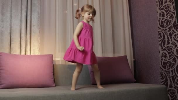 Enfant fille avec haut-parleur sans fil profiter écouter de la musique. Danse sur canapé à la maison — Video