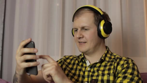 Ευτυχισμένος νεαρός άνδρας χρησιμοποιεί προγράμματα περιήγησης smartphone μέσω του Διαδικτύου, γιορτάζει — Αρχείο Βίντεο