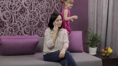 Annem akıllı telefondan konuşmaya çalışıyor. Gürültülü koşan, zıplayan çocuk yüzünden stresli.