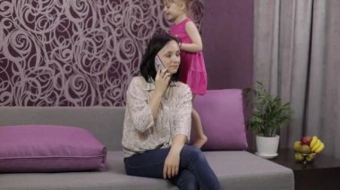 Annem akıllı telefondan konuşmaya çalışıyor. Gürültülü koşan, zıplayan çocuk yüzünden stresli.