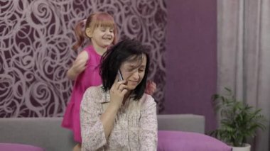 Annem akıllı telefondan konuşmaya çalışıyor. Gürültülü koşan, zıplayan çocuk yüzünden stresli.