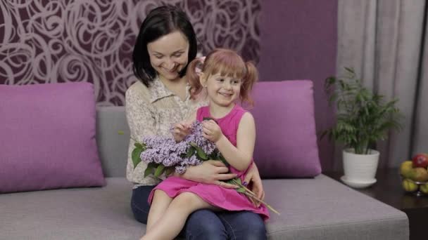 Η μικρή κόρη και η μητέρα κάθονται στη σαπουνόπερα με μπουκέτο πασχαλινά μοβ λουλούδια — Αρχείο Βίντεο