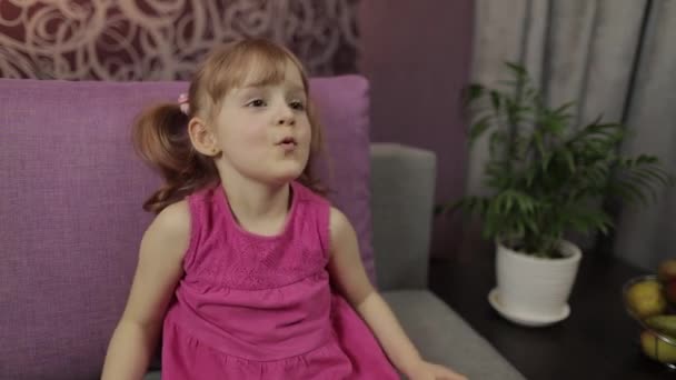 Criança sentada no sofá enquanto assistia TV. Kid menina assistir televisão — Vídeo de Stock