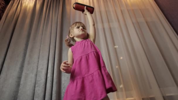Gyermek lány vezeték nélküli hangszóróval élvezi a zenét. Otthon táncolok. — Stock videók