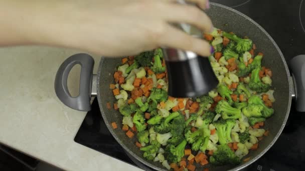 Añadir sal a las verduras frescas en la sartén. Zanahorias, coliflor, brócoli — Vídeos de Stock