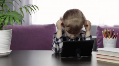 Dijital tablet bilgisayar kullanarak online ödev okuyan bir kız. Uzaklık eğitimi