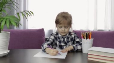 Evde kalemle resim çizen sevimli bir kız çocuğu. Uzaklık eğitimi