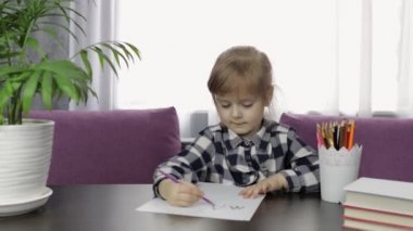 Evde kalemle resim çizen sevimli bir kız çocuğu. Uzaklık eğitimi