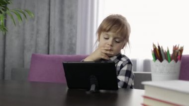 Dijital tablet bilgisayar kullanarak online ödev okuyan bir kız. Uzaklık eğitimi