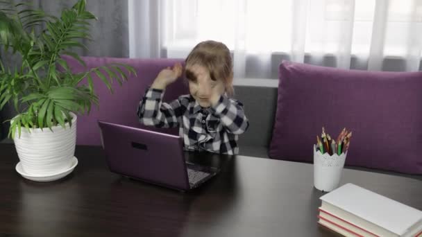 女の子は家庭でデジタルノートパソコンを使ってレッスンをしています。距離教育 — ストック動画