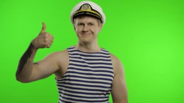 Genç denizci kameraya bakarak başparmağını kaldırdı. Denizci yeleği giyen denizci.