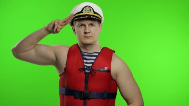 Muscular sailor man works as lifeguard at beach salutes with hand to camera — Stock Video