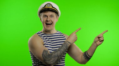 Genç denizci elleri olan bir şeyi işaret ediyor. Denizci yeleği giyen denizci.