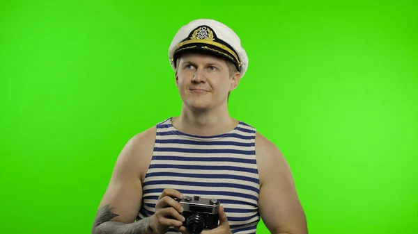 Νεαρός ναύτης τραβάει μια φωτογραφία σε μια ρετρό κάμερα. Ναύτης με γιλέκο ναυτικού. — Φωτογραφία Αρχείου