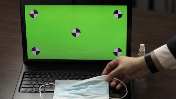 Mans hand neemt ontsmettingsmiddel en gebruik in de buurt laptop met groen scherm. Coronavirus — Stockvideo