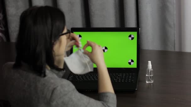 Woman removes medical mask, take sanitizer and use near laptop with green screen — Stock Video