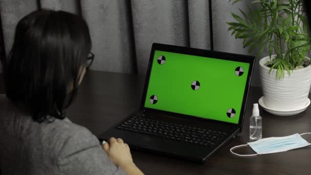 A nő videokonferenciát tart a laptopon, zöld képernyővel. Távolsági munka — Stock videók