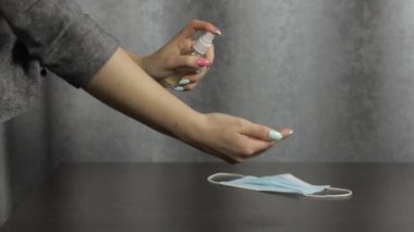 Elleriyle bir şişe sıvı alkol spreyi kullanan bir kadın. Coronavirüs