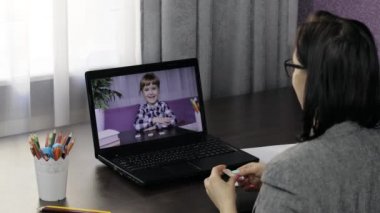 Bayan öğretmen, çocuk öğrencilerle bilgisayardan video görüşmesi yapıyor. Uzaklık eğitimi