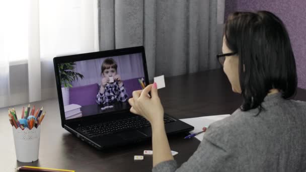 L'insegnante di donna fa la videochiamata su computer portatile con scolaro da bambini. Istruzione a distanza — Video Stock