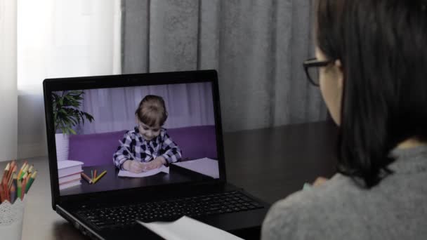 Mujer maestra hace videollamada en portátil con los niños alumno. Educación a distancia — Vídeo de stock