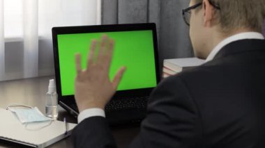 Adamın bilgisayarında yeşil ekranlı video konferansı var. Uzaklık çalışması çevrimiçi