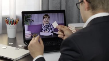 Erkek öğretmen laptopta küçük bir öğrenciyle video görüşmesi yapıyor. Uzaklık eğitimi