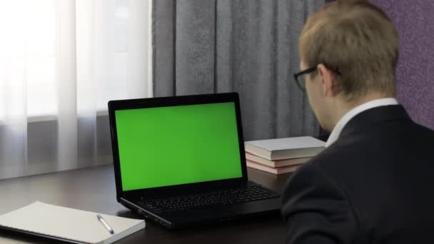 Homem tem videoconferência no laptop com tela verde. Trabalho à distância online — Vídeo de Stock