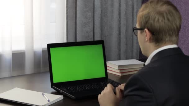 Homem tem videoconferência no laptop com tela verde. Trabalho à distância online — Vídeo de Stock