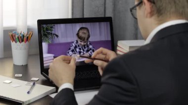 Erkek öğretmen bilgisayardan çocuklarla video görüşmesi yapıyor. Uzaklık eğitimi