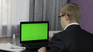 Adamın bilgisayarında yeşil ekranlı video konferansı var. Uzaklık çalışması çevrimiçi