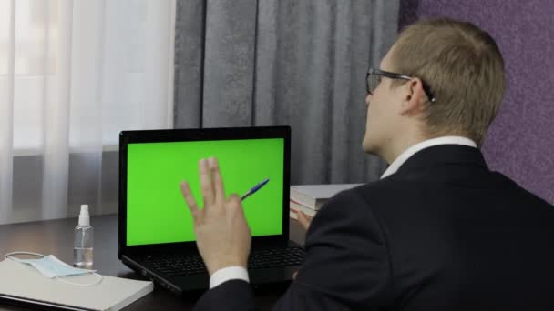 Homem tem videoconferência no laptop com tela verde. Trabalho à distância online — Vídeo de Stock