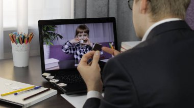 Erkek öğretmen bilgisayardan çocuklarla video görüşmesi yapıyor. Uzaklık eğitimi