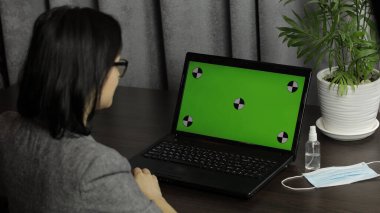 Kadının bilgisayarında yeşil ekranlı video konferansı var. Uzaklık çalışması