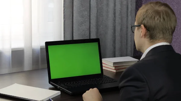 Facet ma wideokonferencję na laptopie z zielonym ekranem. Praca na odległość online — Zdjęcie stockowe