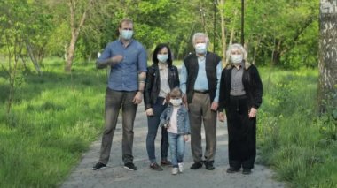 Parktaki büyük aile Coronavirus karantinasından sonra tıbbi maskelerini çıkarıyor.
