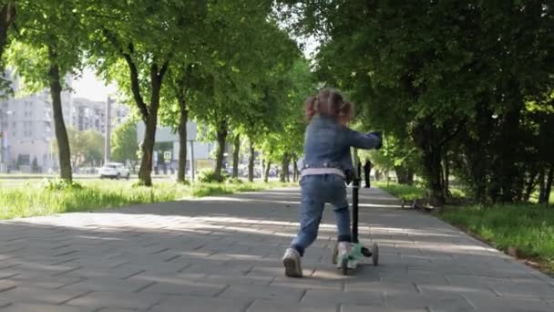 Klein meisje rijdt scooter in groen pring park met moeder en grootouders — Stockvideo