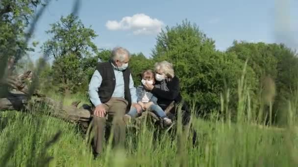 Nonni con nipote in maschere mediche nel parco. Quarantena del coronavirus — Video Stock