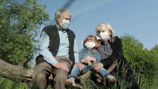 Avós com neta em máscaras médicas no parque. Quarentena do Coronavirus — Vídeo de Stock